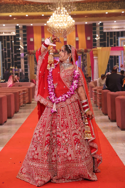 A bride walking a red carpet beneath a chandelier
