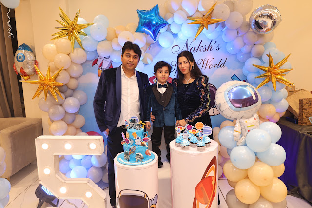 A family beside a balloon arch at a birthday celebration